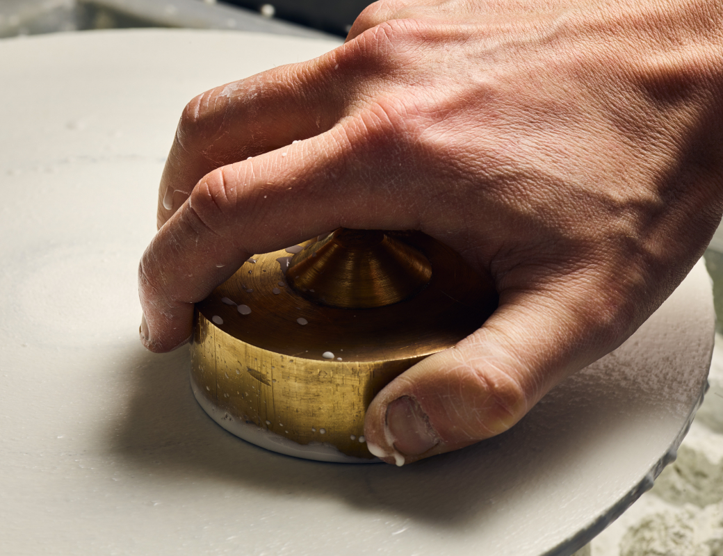 Polishing_the_opal_by_pressing_it_gently_against_a_turntable_covered_with_fine_felt_and_white_cerium_oxide_solution